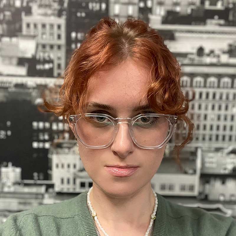 A person in a blue coat standing in front of a large projector screen